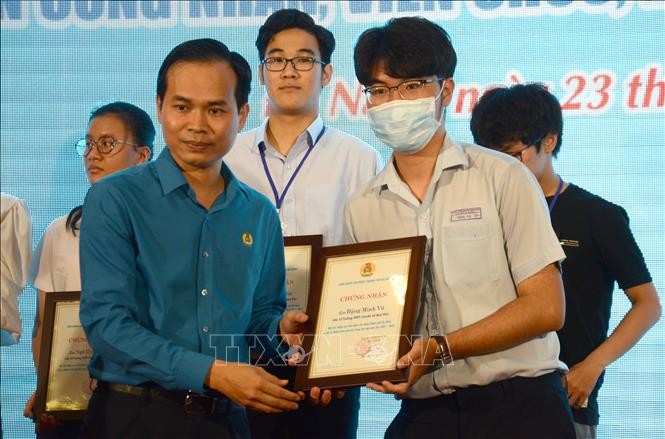 Chủ tịch LĐLĐ thành phố Đà Nẵng Nguyễn Duy Minh (trái) trao học bổng cho học sinh là con công nhân, người lao động (Ảnh: TTXVN).
