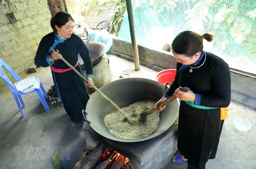 Rang cốm phải đều tay, nhỏ lửa để hạt cốm không bị cháy, không khô, xanh đều (Ảnh: Quốc Khánh/TTXVN).