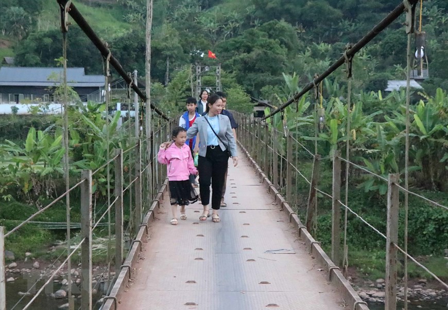 Du khách đi cầu treo Nà Sự vào trung tâm bản của xã Chà Nưa (Ảnh: Xuân Tiến/TTXVN)