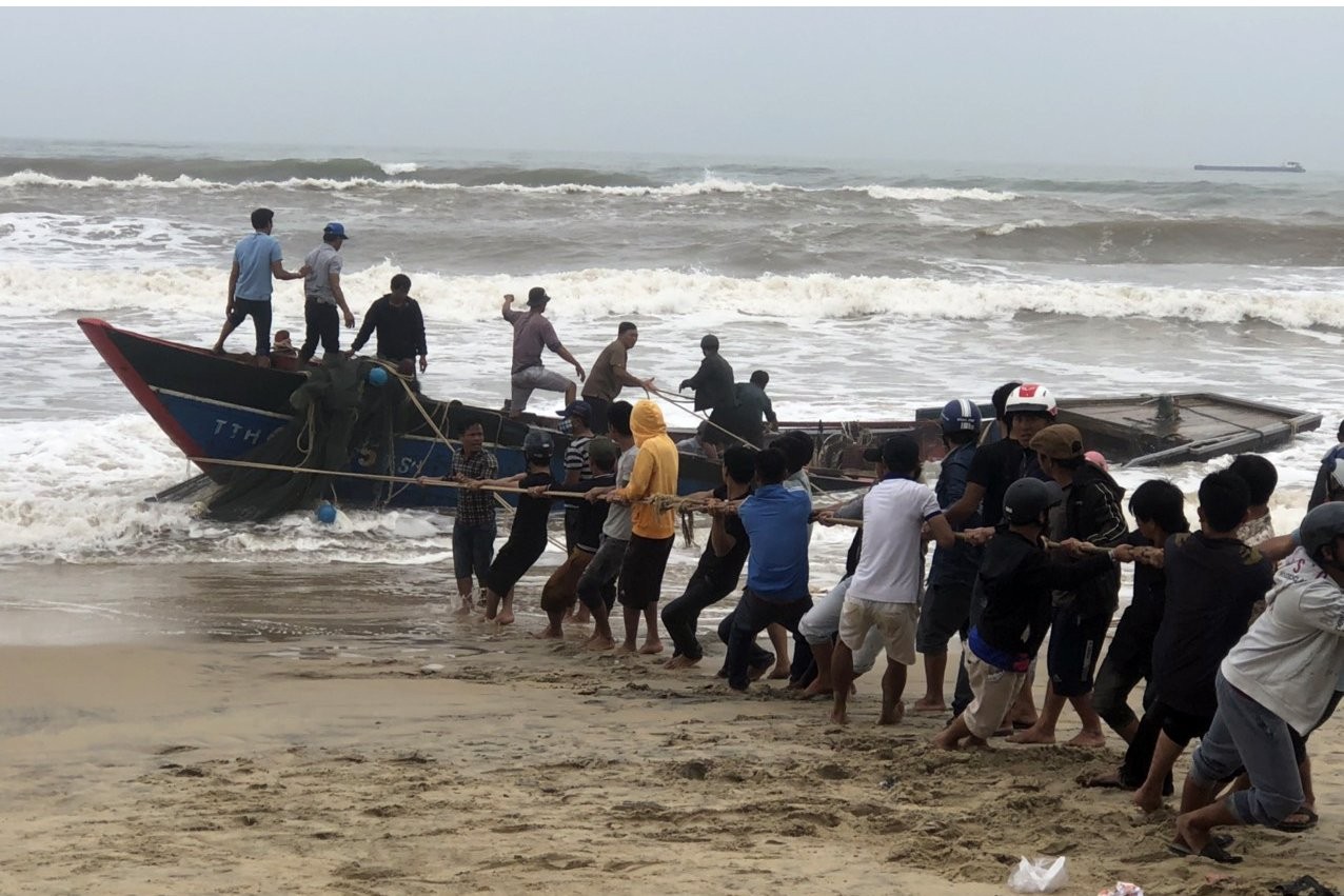 Lực lượng chức năng và người dân trục vớt tàu cá bị nạn. (Ảnh: Võ Tiến)