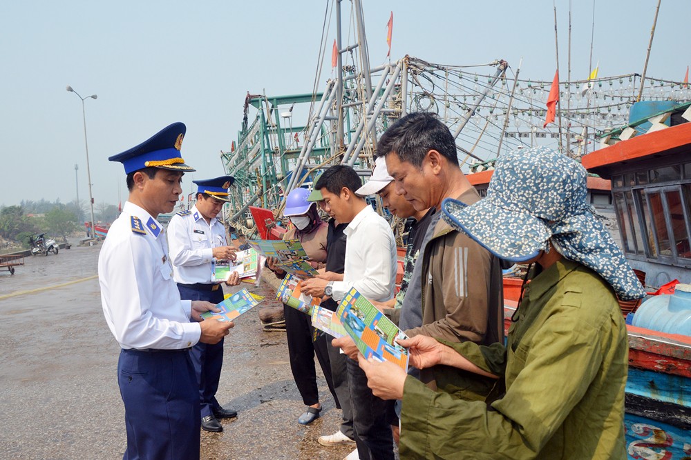 Các chiến sĩ Cảnh sát biển phát tờ rơi tuyên truyền pháp luật cho ngư dân thành phố Sầm Sơn.