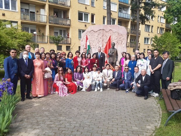 Bà con cộng đồng cùng các vị khách mời Hungary chụp ảnh kỷ niệm bên tượng Bác. (Ảnh: Hoàng Linh/TTXVN).)