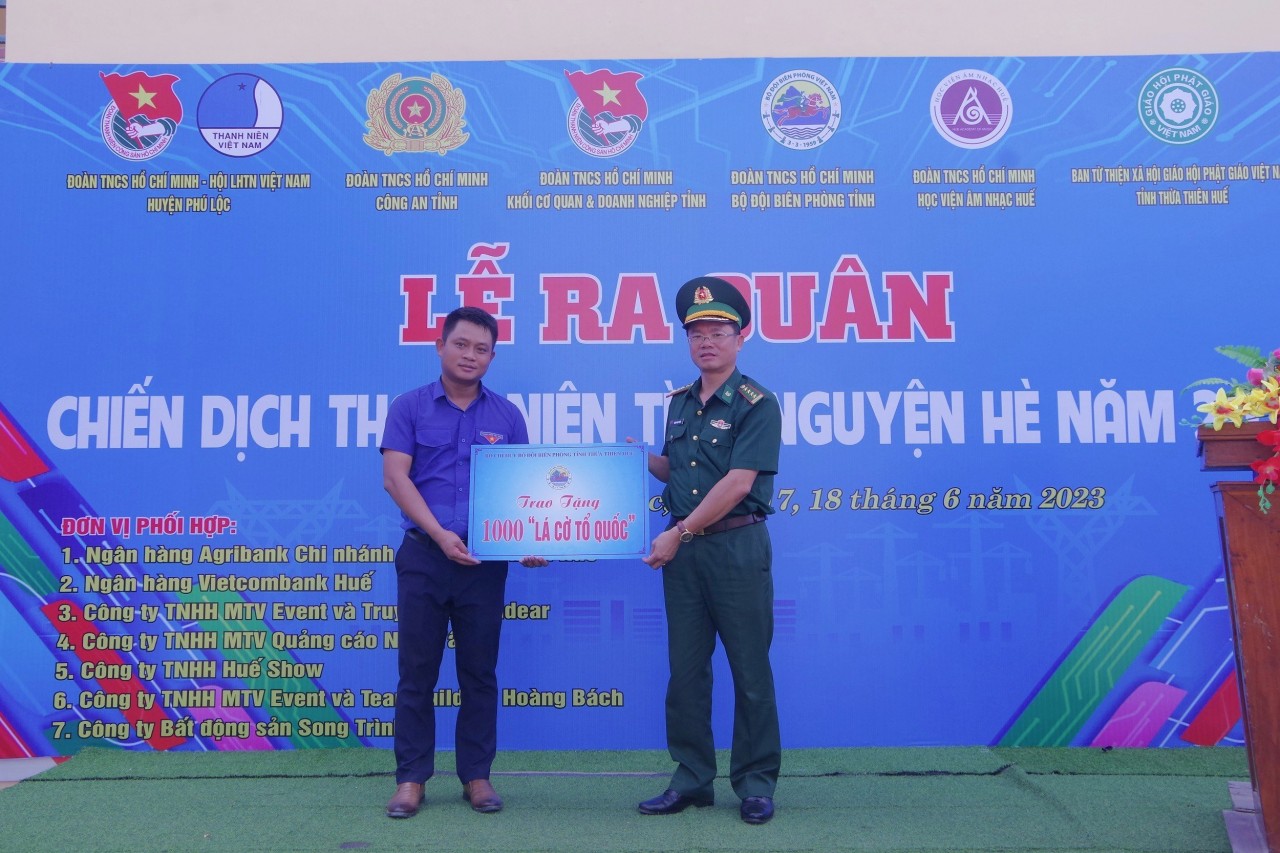 Đại tá Đặng Ngọc Hiệu, Phó Chính ủy BĐBP Thừa Thiên Huế trao biểu trưng tặng 1.000 lá cờ Tổ quốc cho Huyện đoàn Phú Lộc. Ảnh: Võ Tiến