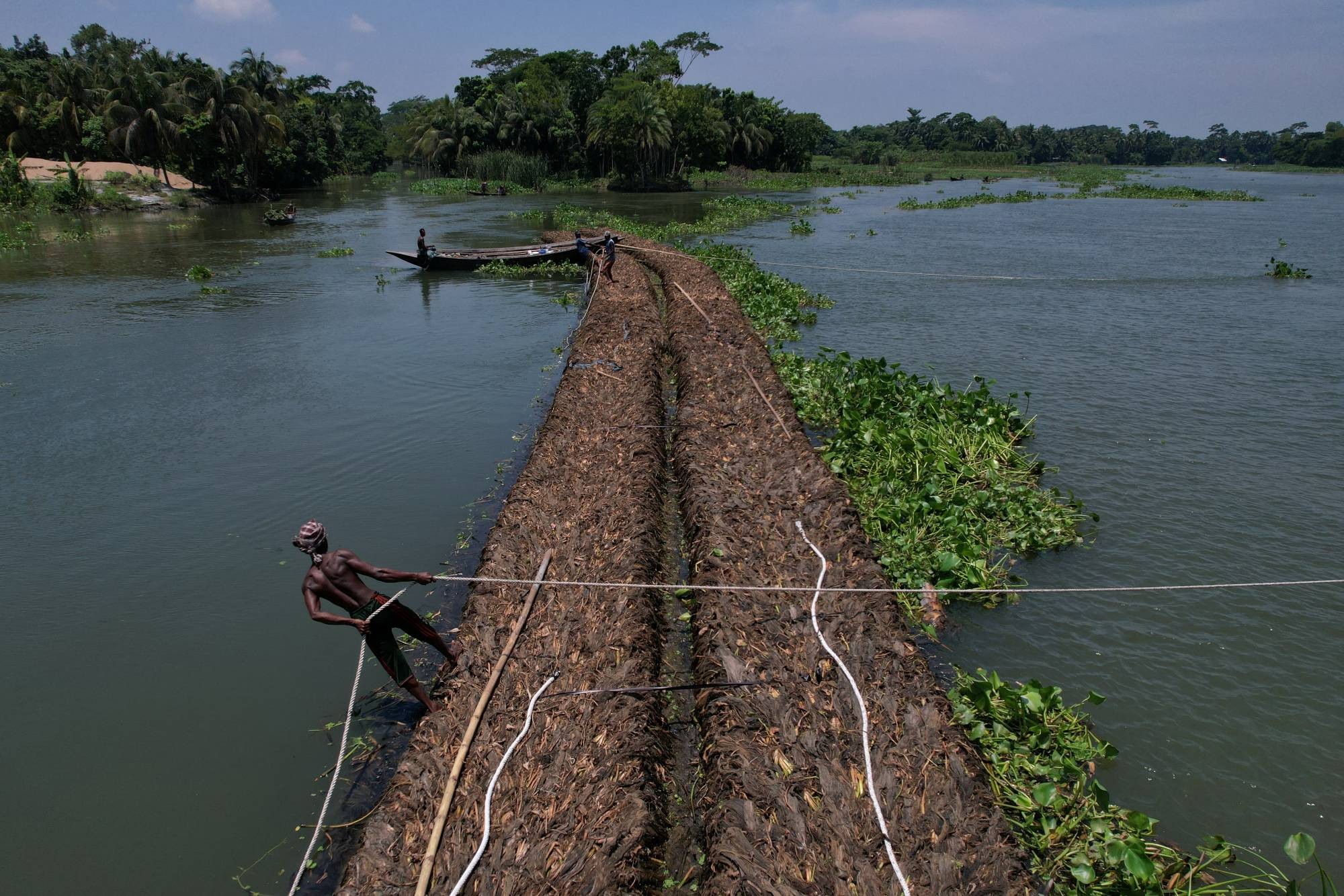 Nông dân ở Pirojpur Bangladesh di chuyển bè nổi trên sông Belua (Ảnh Reuters).