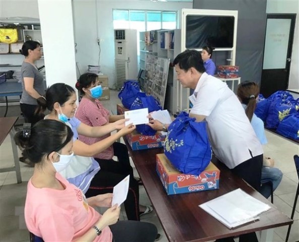 Trao tặng quà trị giá 200.000 đồng cùng 1 triệu đồng tiền mặt cho công nhân Công ty TNHH Pung Kook (Khu chế xuất Tân Thuận) bị mất việc làm. (Ảnh: Thanh Vũ/TTXVN) 
