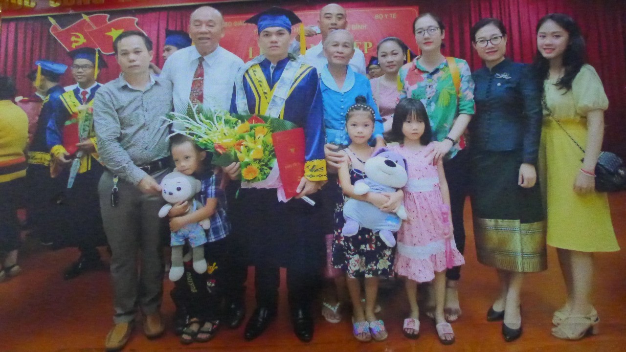Đại tá Nguyễn Đức Hạnh (áo trắng, thứ hai từ trái sang) chụp ảnh cùng gia đình con nuôi Bounpheng trong ngày Bounpheng nhận bằng tốt nghiệp (Ảnh: Đức Hạnh).