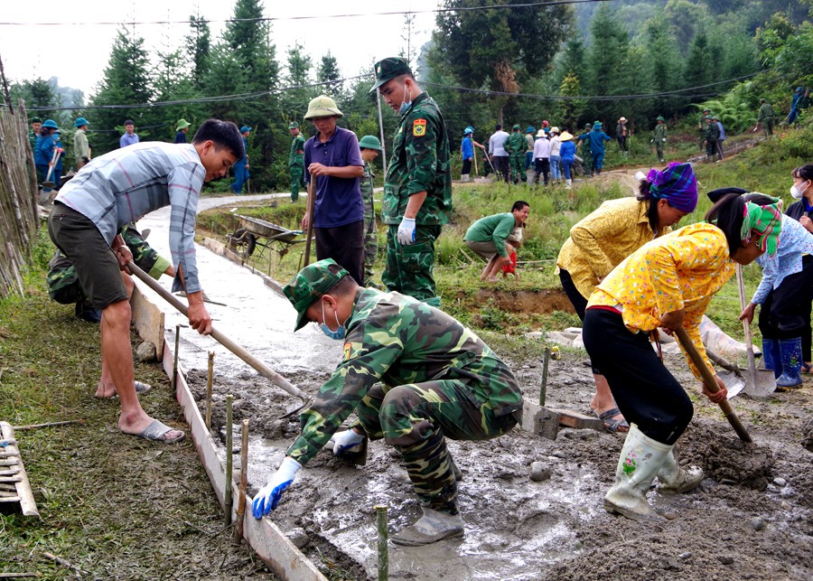 Cán bộ, chiến sỹ Đồn Biên phòng Bản Máy giúp nhân dân làm đường bê tông. (Ảnh: Báo Hà Giang)