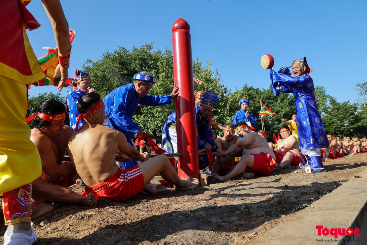 Trong ảnh, hai đội kéo co của đền Trấn Vũ trình diễn trò kéo co ngồi. Dây song được luồn qua một cột gỗ lim lớn, người chơi ngồi chân co, chân duỗi và xen kẽ nhau để có được lực kéo tốt nhất. (Ảnh: Tổ quốc)