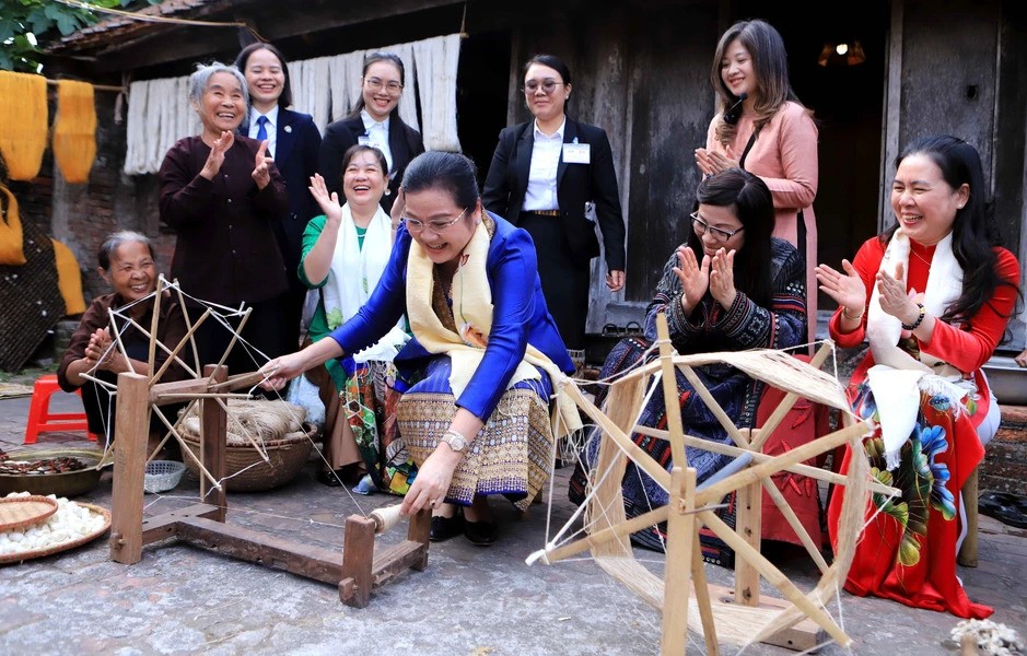 Bà Vandara Siphandone, phu nhân Thủ tướng Chính phủ Lào trực tiếp trải nghiệm công đoạn sản xuất lụa đũi. (Ảnh: TTXVN)