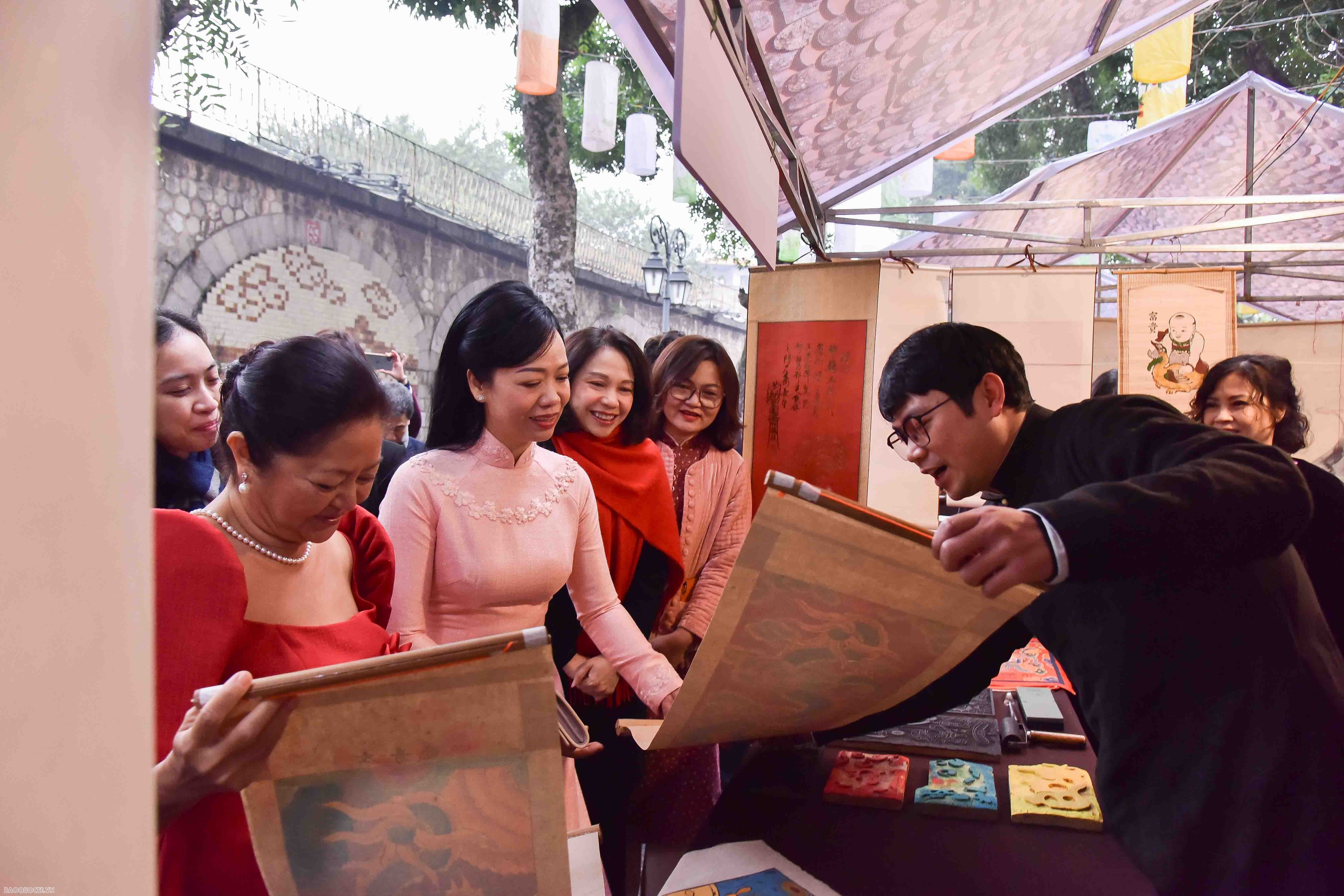 Hai Phu nhân dừng chân tại cửa hàng bán tranh trang trí Tết và ngắm tranh hình con Rồng - con vật của năm Giáp Thìn... (Ảnh: Nguyễn Hồng)