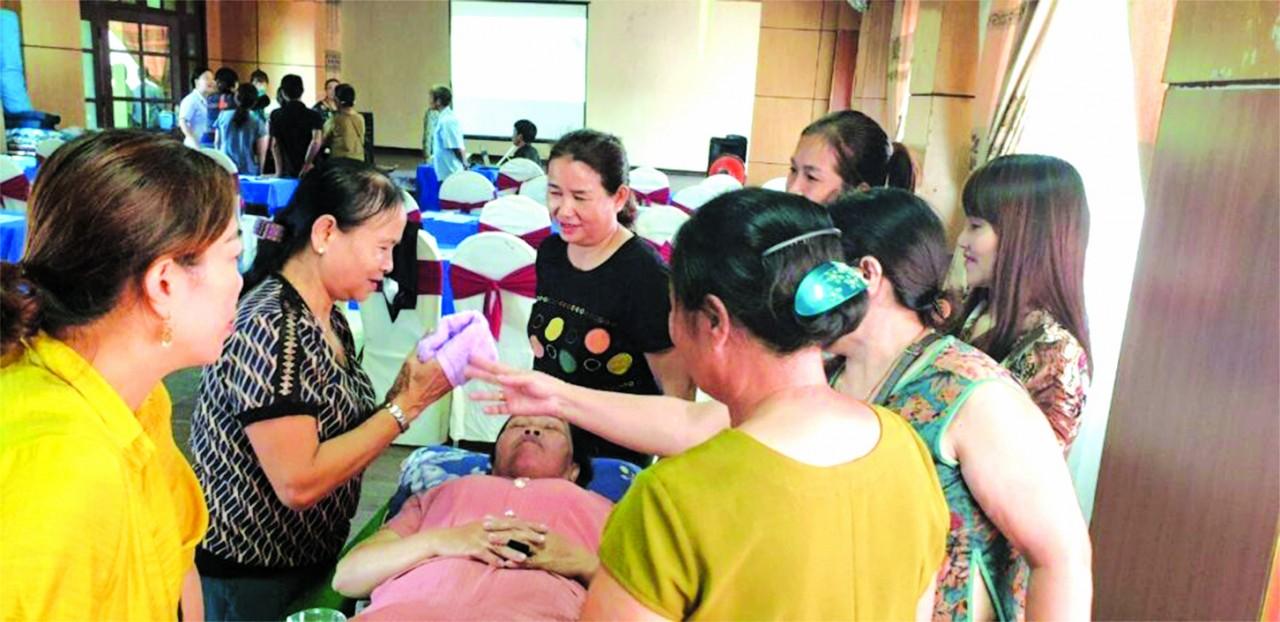 Bà Hoàng Thị Tốt (thứ hai từ trái sang phải) đang thực hành vệ sinh mắt, mũi, tai cho người khuyết tật tại lớp học. (Ảnh: MCNV).