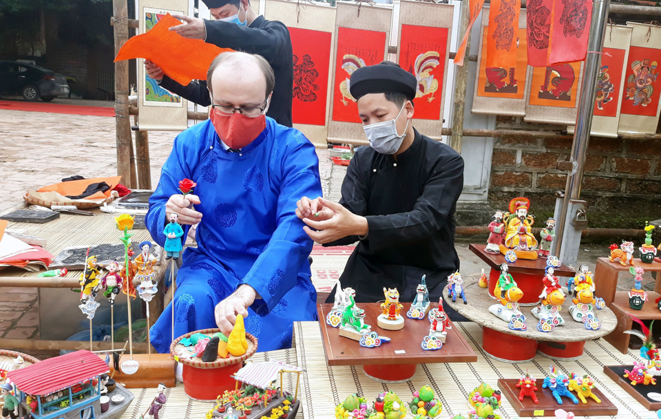 Khách quốc tế trải nghiệm chuẩn bị Tết tại làng cổ Đường Lâm trong dịp Tết Nguyên đán. Ảnh: 