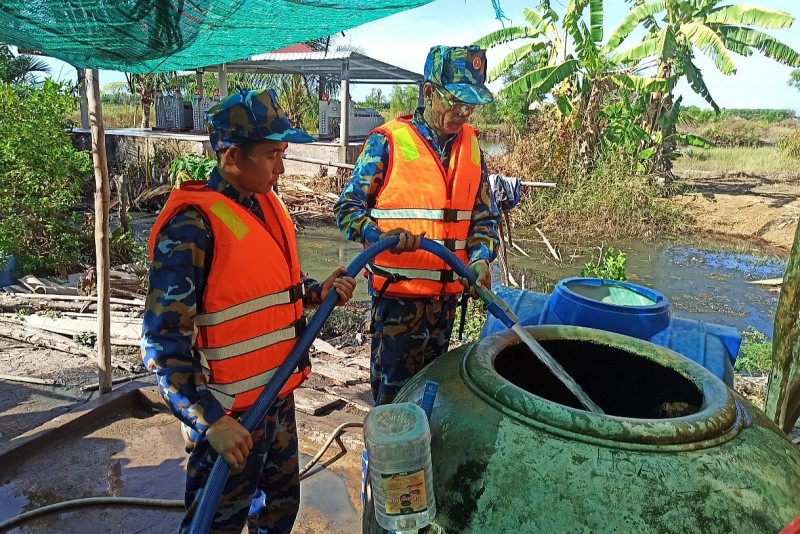 Cán bộ, chiến sĩ Tàu 471 phối hợp với chính quyền địa phương đưa nước đến tận nhà cấp cho người dân.