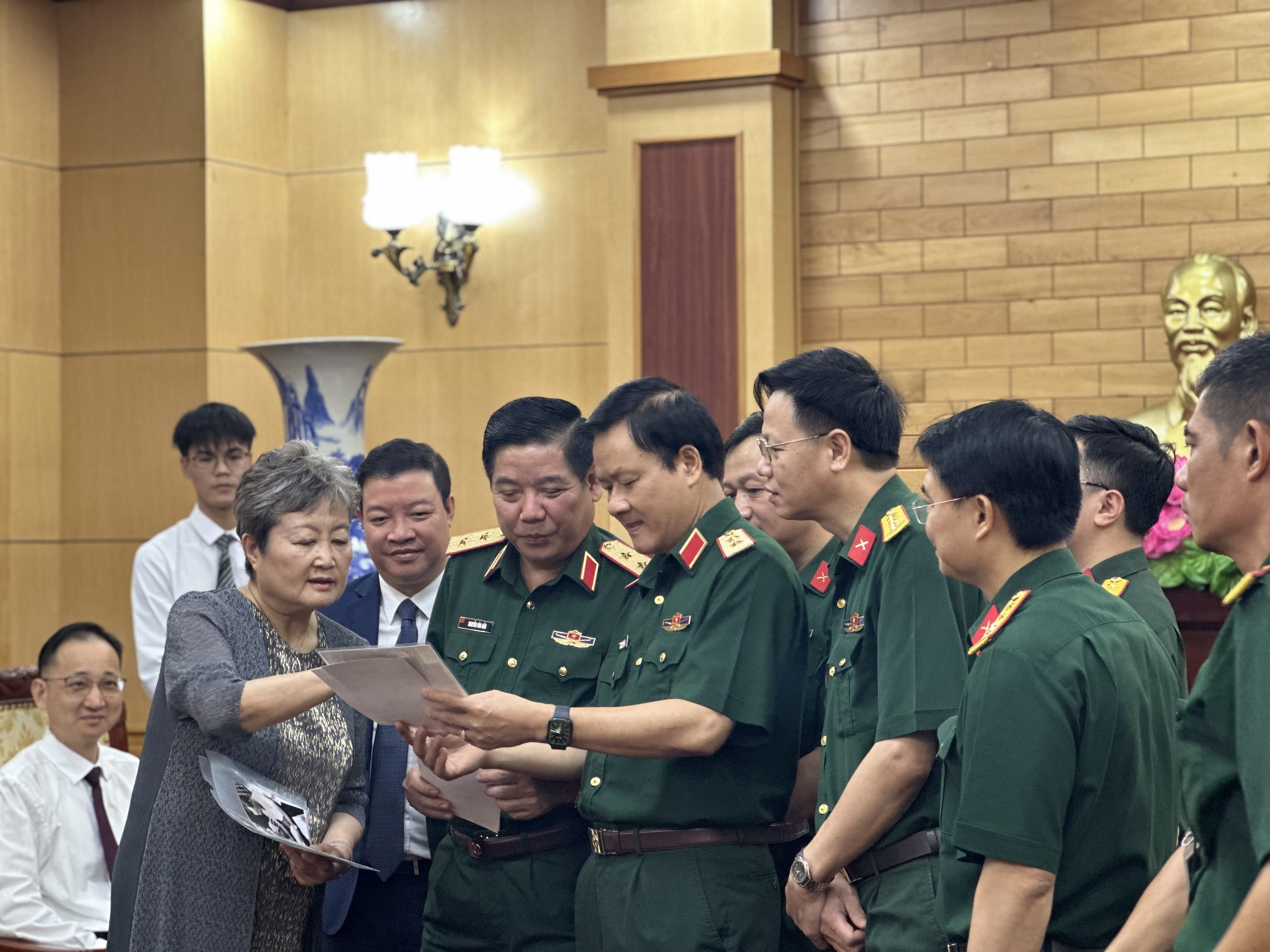 Bà Trần Tri Tiến, con gái đồng chí Trần Canh, giới thiệu với Trung tướng Nguyễn Văn Gấu và các đại biểu dự buổi tiếp những bức ảnh kỷ niệm của gia đình. 