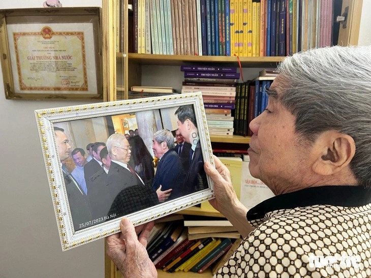 Giáo sư Hà Minh Đức bồi hồi xem lại tấm ảnh chụp cùng học trò cũ Nguyễn Phú Trọng trong dịp kỷ niệm 75 năm Ngày thành lập Liên hiệp các hội văn học nghệ thuật Việt Nam. (Ảnh: Tuổi trẻ)