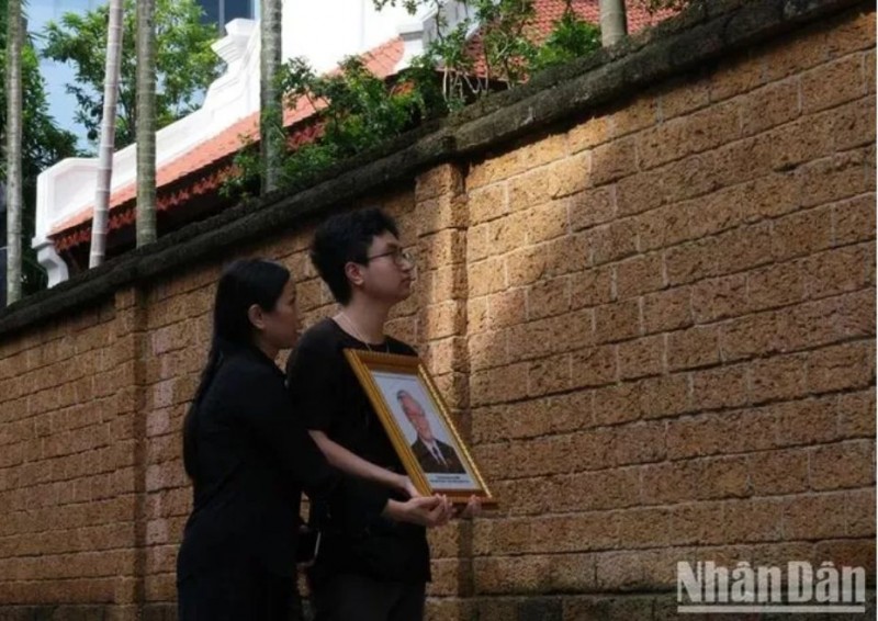 Hai mẹ con chị Lan cầm di ảnh hướng về ngôi nhà của Tổng Bí thư tại làng Lại Đà.