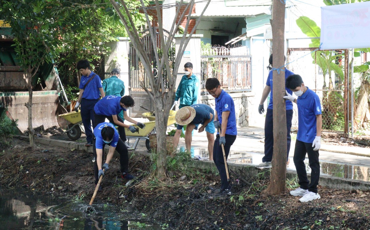 Các sinh viên tình nguyện khơi thông dòng chảy ở mương thoát nước đường số 40, phường Linh Đông, thành phố Thủ Đức, tháng 6/2023.