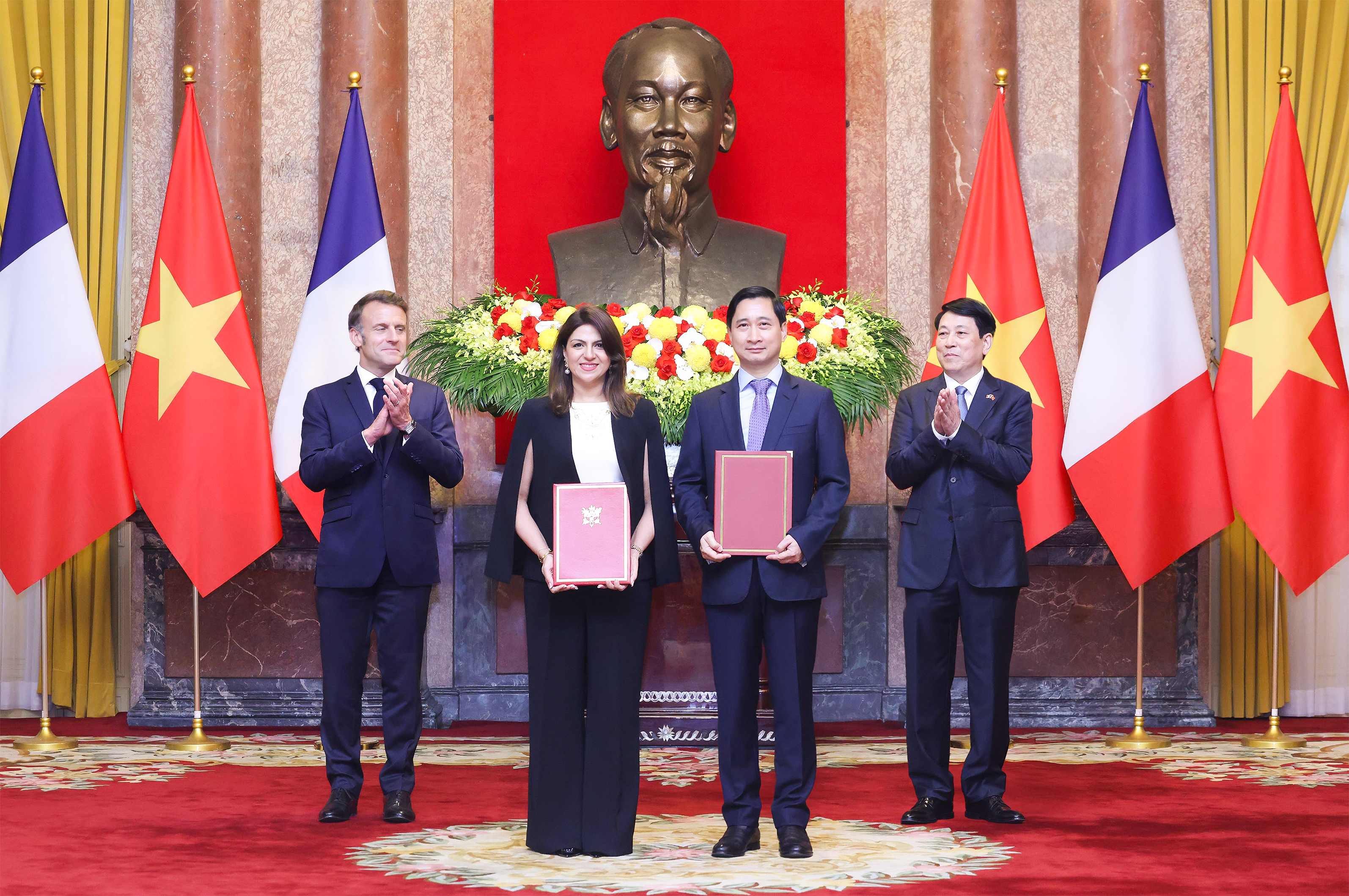 Ông Ngô Chí Dũng, Tổng Giám đốc kiêm Chủ tịch HĐQT Công ty Vắc xin Việt Nam (VNVC) và bà Zainab Sadat Qayyum, Chủ tịch Sanofi vùng Đông Nam Á - Ấn Độ trao văn kiện thỏa thuận hợp tác chuyển giao công nghệ sản xuất vắc xin của Sanofi tại Nhà máy Vắc xin và Sinh phẩm VNVC trước sự chứng kiến của Chủ tịch nước Lương Cường và Tổng thống Pháp Emmanuel Macron. Ảnh: Lâm Khánh