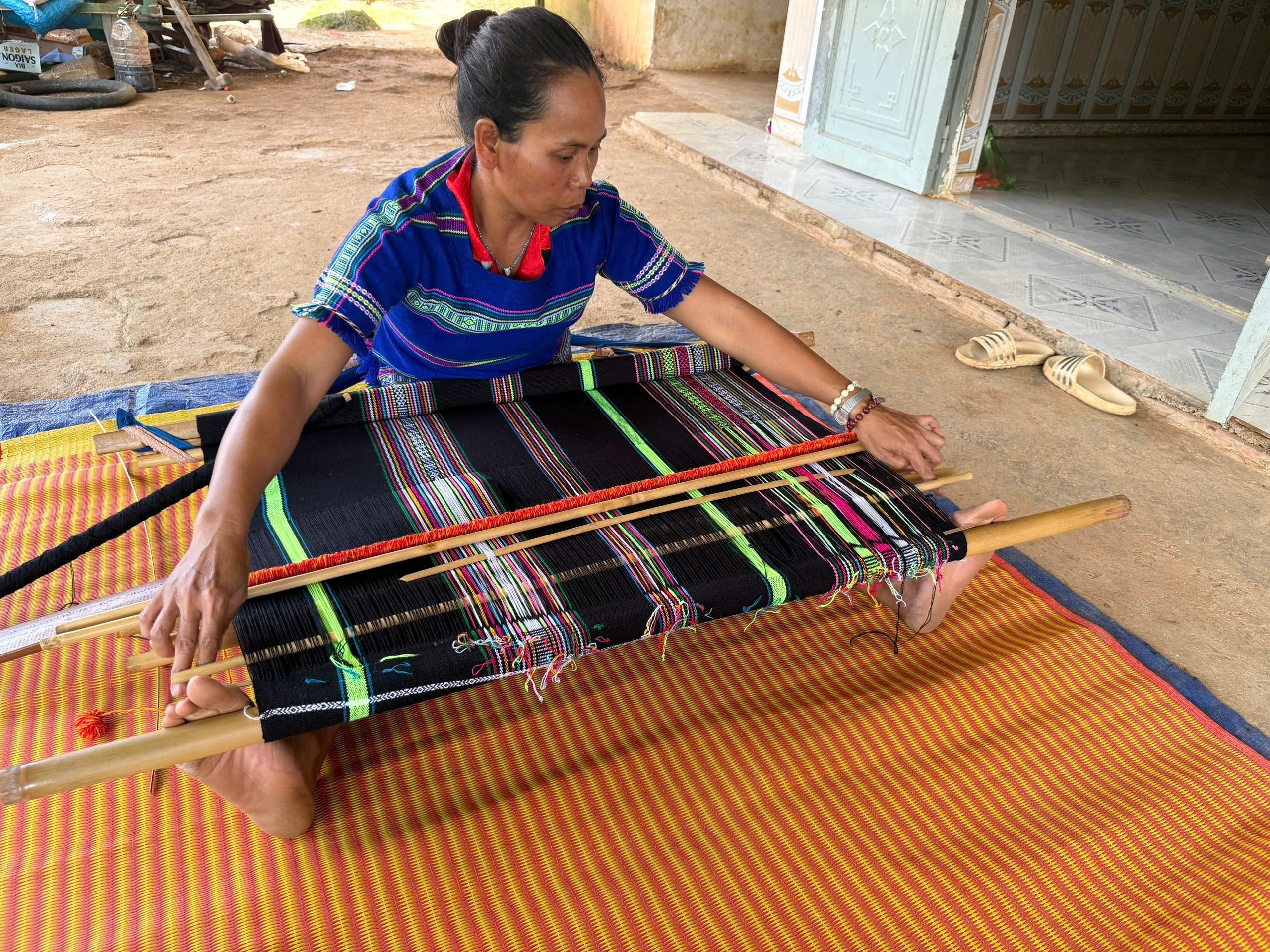 Chị Cil K’Phang luồn thoi dệt thổ cẩm. (Ảnh: Phạm Hưng)