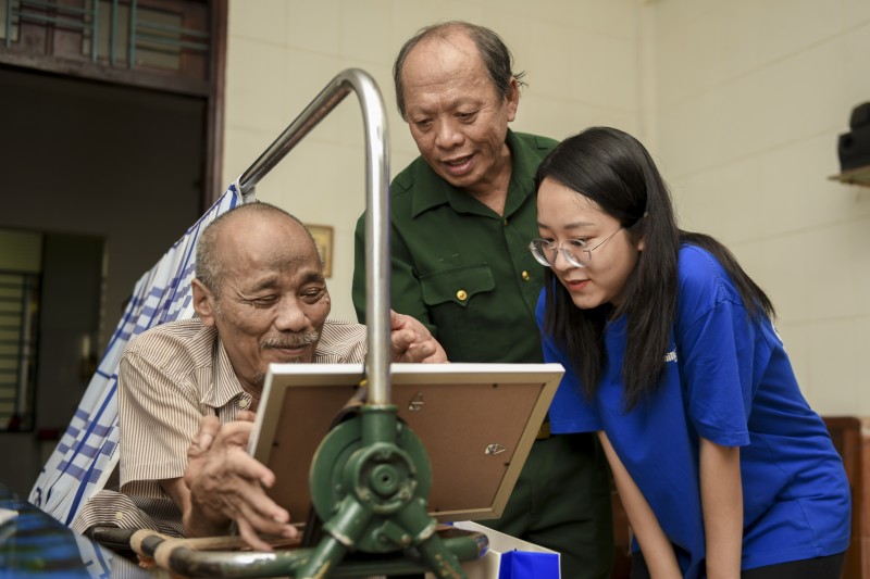 Các bác cựu chiến binh chăm chú đọc những dòng chữ nhỏ, được các em gửi kèm trong mỗi bức tranh (Ảnh: Duy Cường).