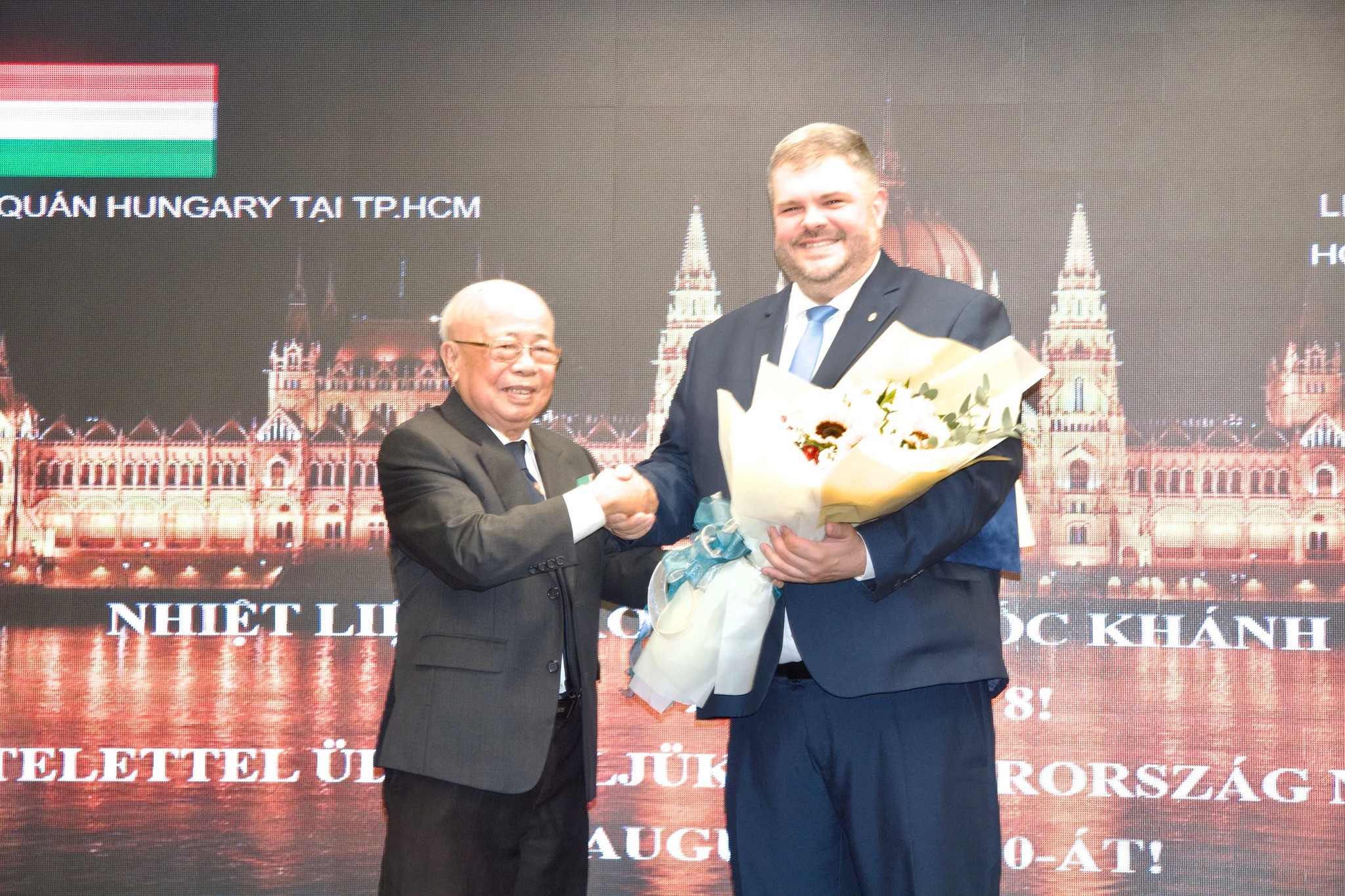 Ông Lê Minh Triết - Chủ tịch Hội hữu nghị Việt Nam - Hungary TPHCM - gửi bó hoa đến Ngài Tổng lãnh sự Hungary tại TPHCM Lehőcz Gábor. (Ảnh: Liên hiệp các tổ chức hữu nghị TP.HCM)