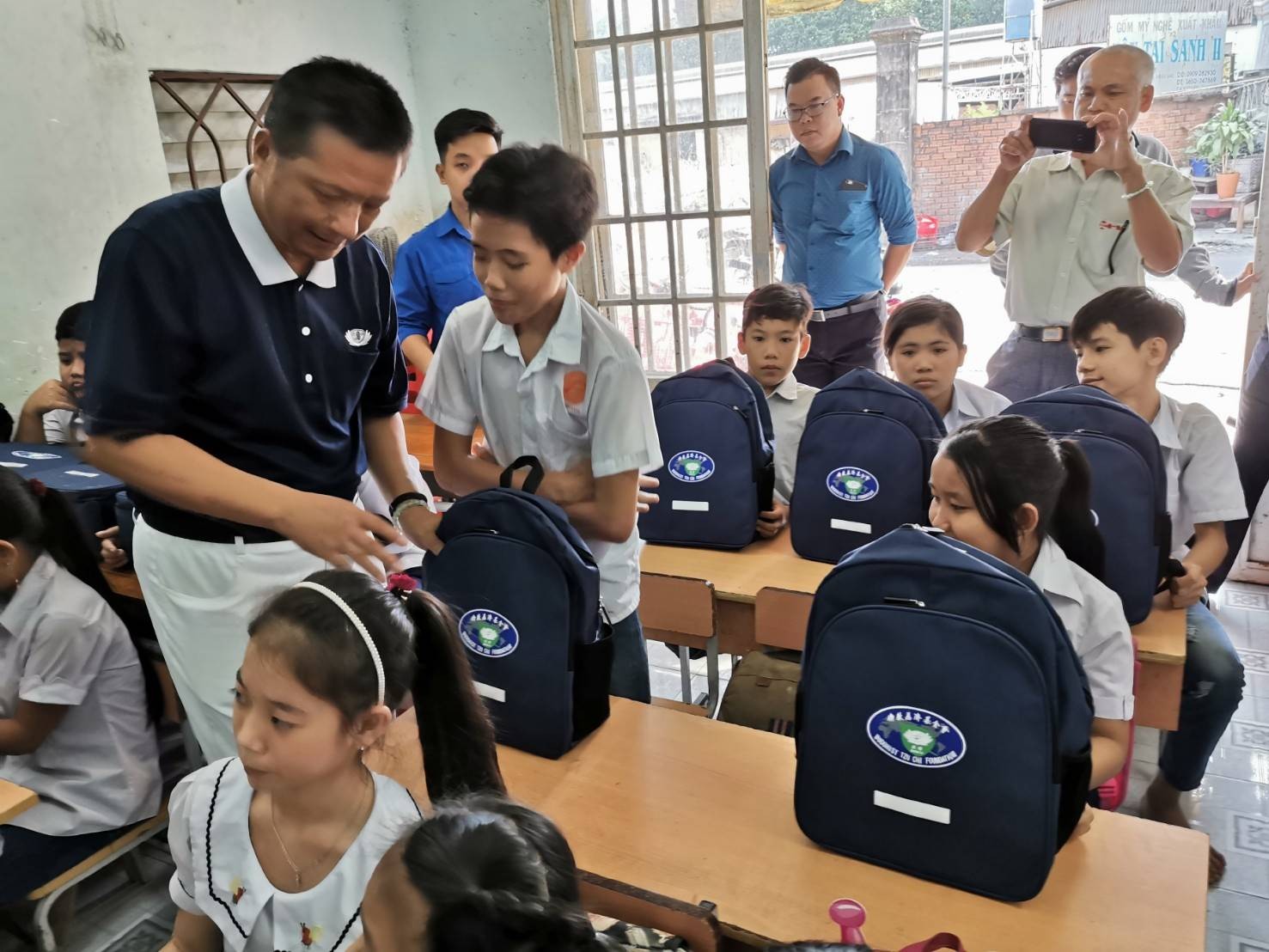Ông Chen Ta Yu (bìa trái) tặng balo và dụng cụ học tập cho lớp học tình thương ở Bình Dương (nay là thành phố Hồ Chí Minh) ngày 26/11/2019. (Ảnh: Tzu Chi)