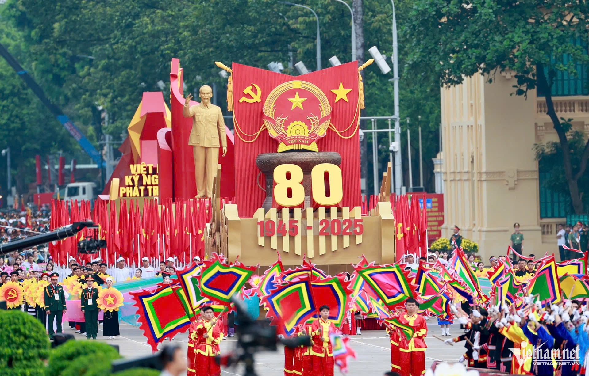 Bốn khối nghi trượng mở đầu đội hình diễu binh, diễu hành. Xe rước Quốc huy với thân xe được phát triển từ họa tiết chèo thuyền gắn với trống đồng; 54 thanh niên đại diện 54 dân tộc. Tiếp đến là nghi trượng rước cờ Tổ quốc, cờ Đảng; xe rước chân dung Chủ tịch Hồ Chí Minh và biểu tượng 80 năm Quốc khánh. (Ảnh: VietNamNet)