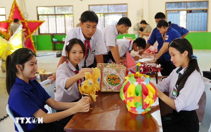 Các em học sinh Việt Nam-Lào cùng nhau làm đèn lồng đón Tết Trung thu. (Ảnh: TTXVN)