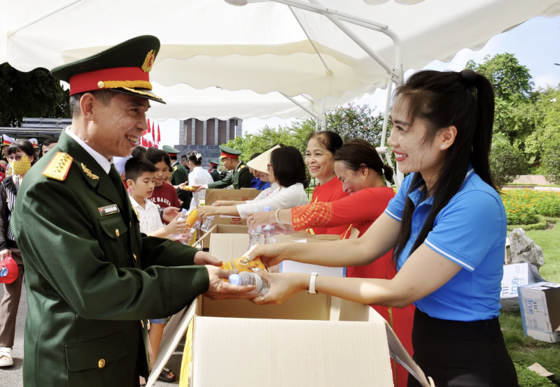 Người dân phấn khởi nhận quà của ngành du lịch trao tặng khi vào lăng viếng Bác. (Ảnh: T.L)