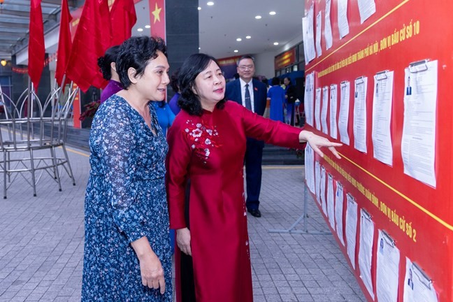 Ủy viên Bộ Chính trị, Bí thư Trung ương Đảng, Chủ tịch Ủy ban Trung ương Mặt trận Tổ quốc Việt Nam Bùi Thị Minh Hoài cùng cử tri nghiên cứu danh sách niêm yết tại khu vực bầu cử