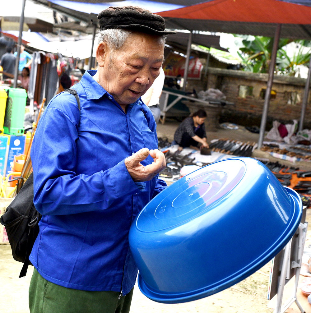 Người đàn ông Mông đang kiểm tra chất lượng chiếc chậu nhựa mà ông muốn mua