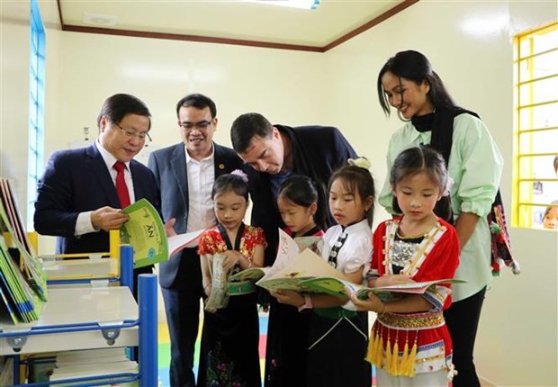 Các đại biểu cùng học sinh điểm trường Sân Bay, Trưởng Tiểu học Phúc Than, huyện Than Uyên tham quan thư viện. Ảnh: Đinh Thùy/TTXVN