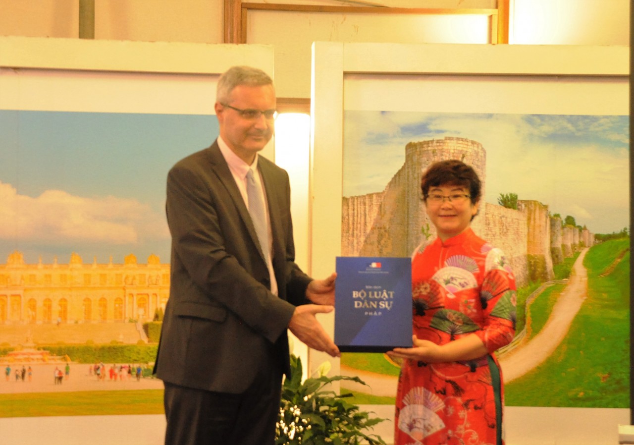 Đại sứ Nicolas Warnery trao  tượng trưng bản dịch Bộ luật Dân sự Pháp dưới dạng một cuốn sách cho đại diện Bộ Tư pháp Việt Nam.