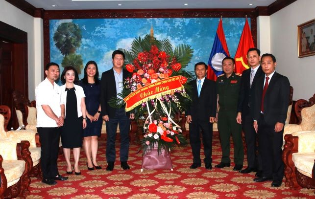 Đồng chí Nguyễn Quế Lâm, Vụ trưởng Vụ Thông tin đối ngoại và Hợp tác quốc tế, Ban Tuyên giáo Trung ương tặng hoa chúc mừng Đại sứ quán Lào. (Ảnh: TA)