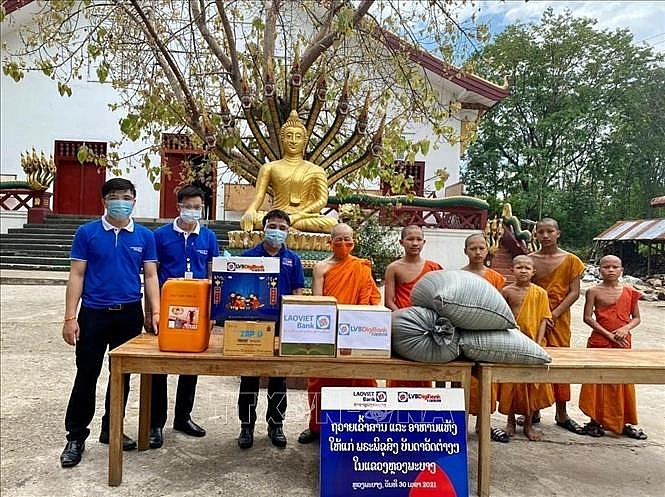 Ngân hàng Lào Việt chi nhánh Luang Prabang trao quà cho các chư tăng để hỗ trợ phòng chống dịch bệnh COVID-19. (Ảnh: TTXVN)