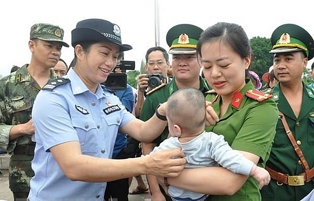 Lực lượng chức năng Việt Nam tiếp nhận em bé bị bán sang Trung Quốc. (Nguồn: TTXVN)