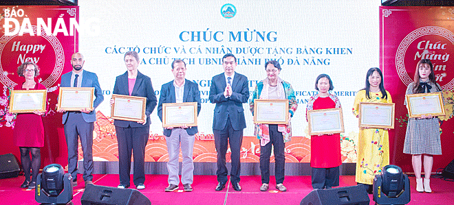 Chủ tịch UBND thành phố Lê Trung Chinh (giữa) tặng bằng khen cho bà Cécile Le Pham (thứ tư, từ phải sang), Phó Chủ tịch Tổ chức ASSORV Pháp và các tổ chức, cá nhân trong dịp gặp mặt người nước ngoài Xuân Tân Sửu 2021. (Ảnh: Báo Đà Nẵng)