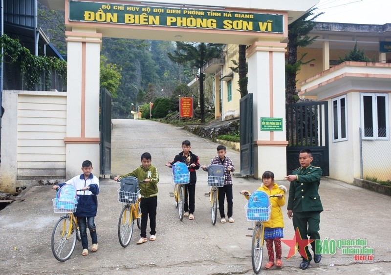 Cán bộ Đồn Biên phòng Sơn Vĩ (Bộ đội Biên phòng tỉnh Hà Giang) dẫn các con nuôi của đồn xuống đường để đến trường. Ảnh: VĂN CHIỂN