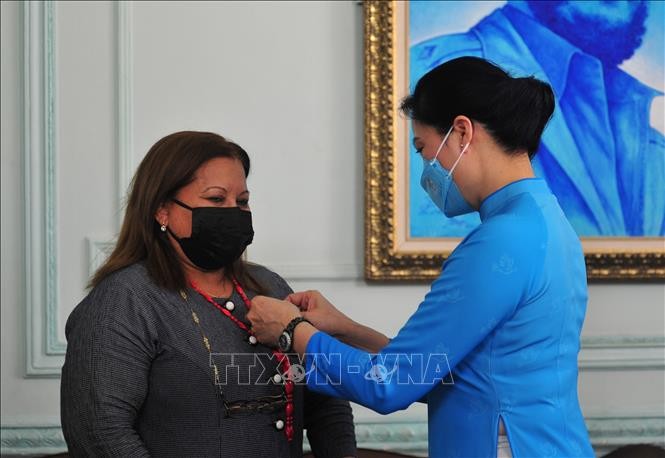 Hà Thị Nga gắn huy hiệu của Hội Liên hiệp Phụ nữ Việt Nam cho đồng chí Teresa Amarelle Boué. Ảnh: Vũ Hà/TTXVN