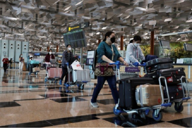 Du khách đẩy hành lý tại sân bay Changi. Ảnh: Reuters