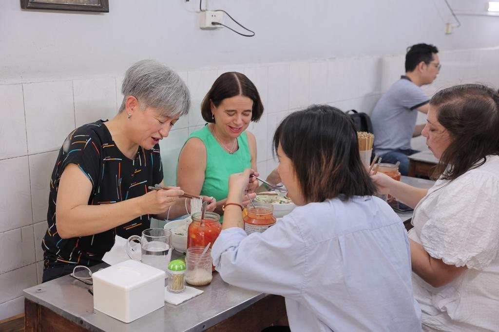 Ngoại trưởng Wong (áo đen) thưởng thức phở gà cùng Đại sứ Mudie (áo xanh) trong ảnh được công bố hôm nay. Ảnh: Đại sứ quán Australia tại Việt Nam.