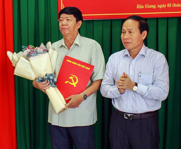 Bí thư Tỉnh ủy Lê Tiến Châu (phải) trao quyết định cho ông Lê Văn Tông (Ảnh: Báo Hậu Giang)