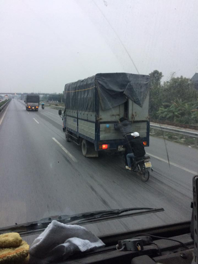 hinh anh nam thanh nien dung tren xe may du bam xe tai day nguy hiem