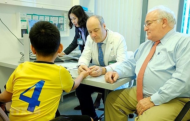 Bác sỹ Stéphane Guero (giữa) khám cho một bệnh nhi bị dị dạng ngón tay. Ảnh: TTXVN